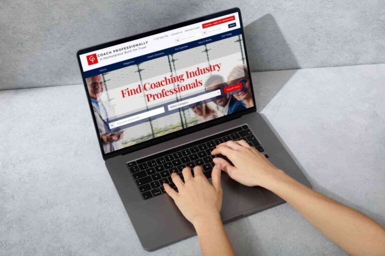 Hands swiftly typing on a laptop displaying a website titled “Find Coaching Industry Professionals.” Among the navigation menus and search functionality, it showcases life coaching directories, all set against a backdrop of office windows.